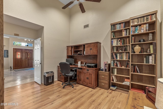 office space featuring ceiling fan, light hardwood / wood-style flooring, and a high ceiling