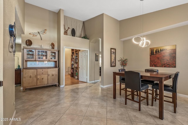 tiled dining space with a chandelier and a high ceiling