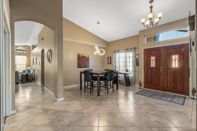 tiled foyer with high vaulted ceiling, a wealth of natural light, and a chandelier