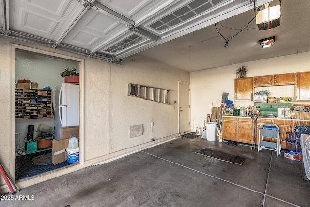 garage featuring white fridge and a garage door opener