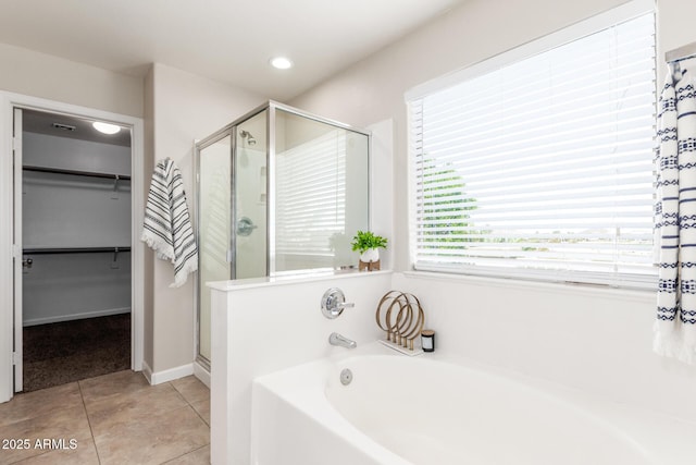 full bathroom with a walk in closet, tile patterned floors, a bath, and a stall shower