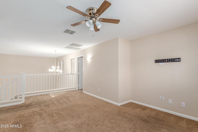 carpeted empty room with ceiling fan with notable chandelier, baseboards, and visible vents