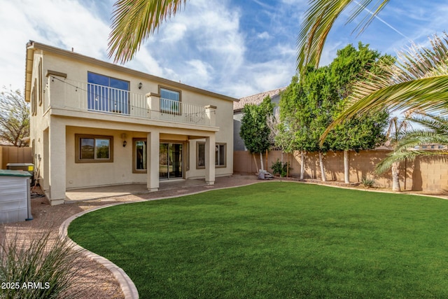 rear view of house with a fenced backyard, stucco siding, and a balcony