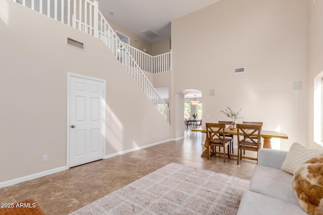 living room with arched walkways, visible vents, and baseboards