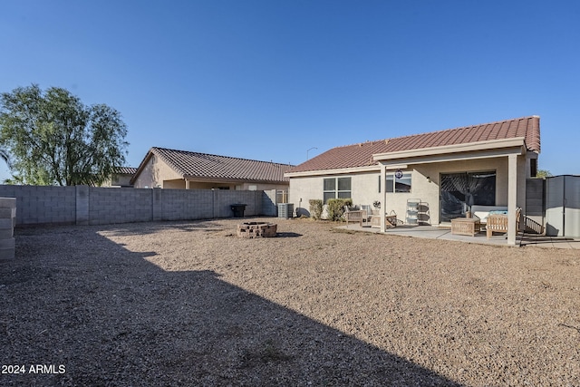 rear view of house featuring a fire pit, central AC unit, and a patio area