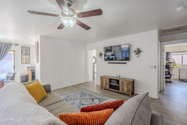 living room with ceiling fan, light hardwood / wood-style flooring, and a textured ceiling