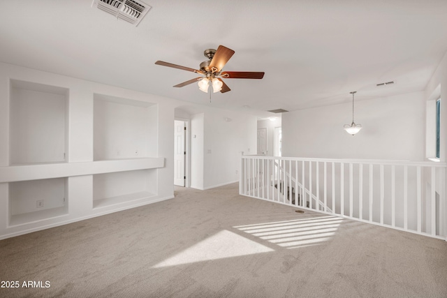 unfurnished room featuring carpet flooring, built in features, and ceiling fan