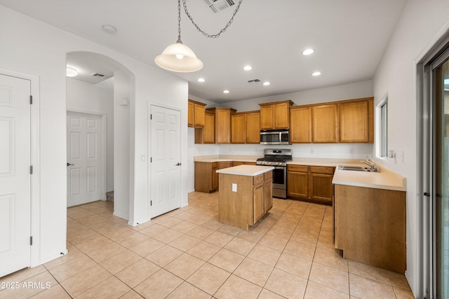 kitchen with stainless steel appliances, sink, light tile patterned floors, decorative light fixtures, and a center island