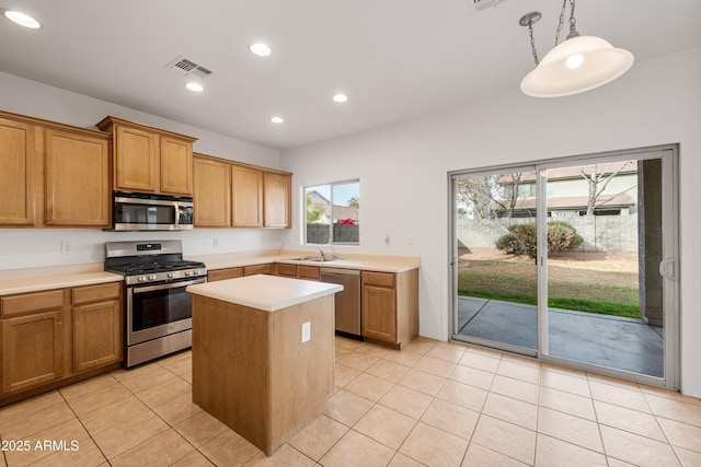 kitchen featuring pendant lighting, plenty of natural light, a kitchen island, and appliances with stainless steel finishes