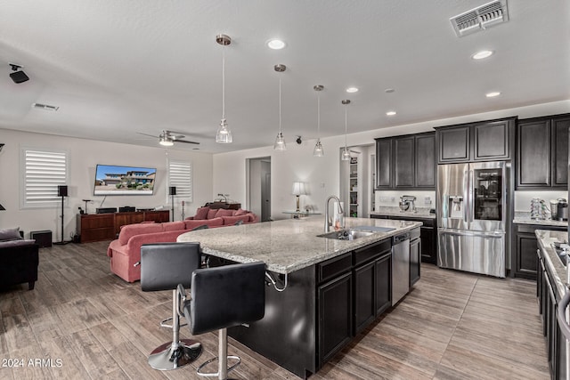 kitchen featuring pendant lighting, sink, a kitchen island with sink, appliances with stainless steel finishes, and a kitchen breakfast bar