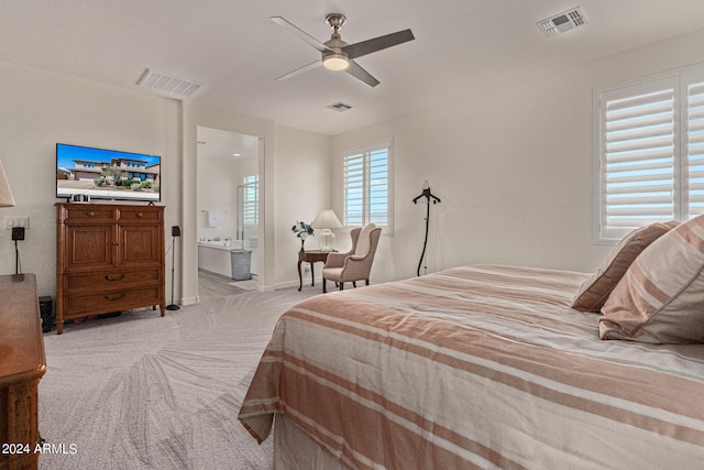 bedroom featuring light carpet, ensuite bath, and ceiling fan