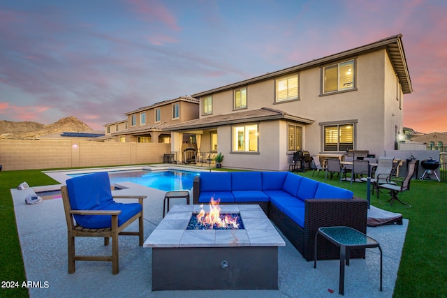 pool at dusk with an outdoor living space with a fire pit and a patio area