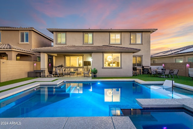 back house at dusk with a patio and a fenced in pool