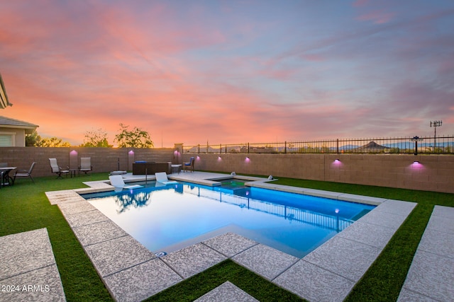 pool at dusk featuring a lawn and a patio area