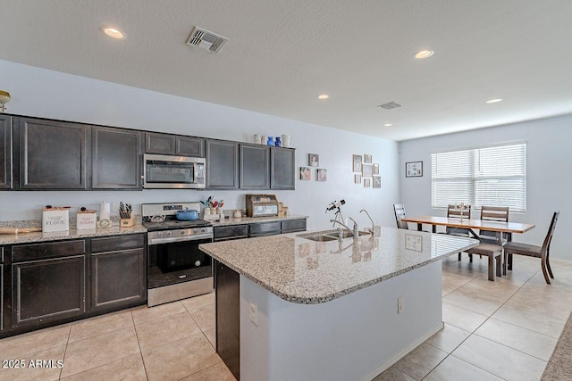 kitchen with an island with sink, light tile patterned floors, appliances with stainless steel finishes, and sink