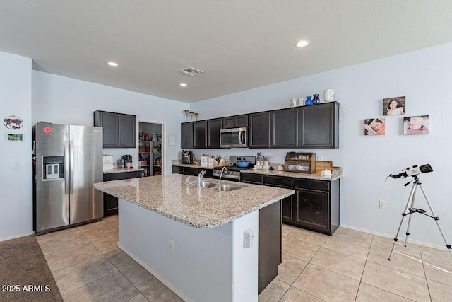 kitchen featuring light tile patterned floors, appliances with stainless steel finishes, sink, and an island with sink