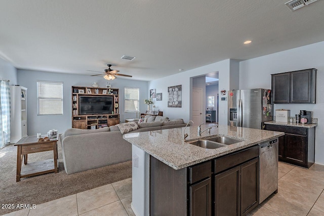 kitchen featuring stainless steel appliances, a center island with sink, dark brown cabinetry, and sink