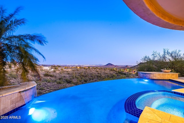 view of swimming pool with a mountain view and a pool with connected hot tub