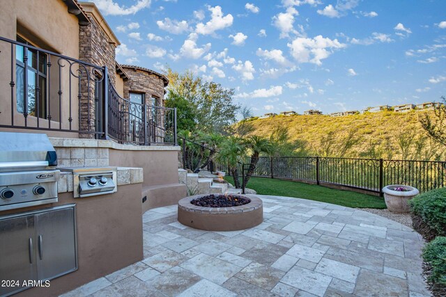 view of patio / terrace featuring grilling area, a fire pit, an outdoor kitchen, and fence