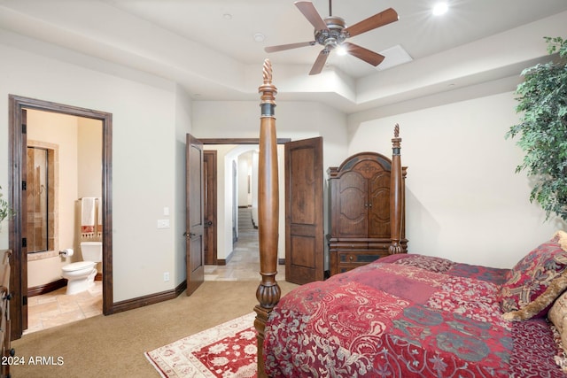 bedroom featuring baseboards, a tray ceiling, ceiling fan, light carpet, and connected bathroom