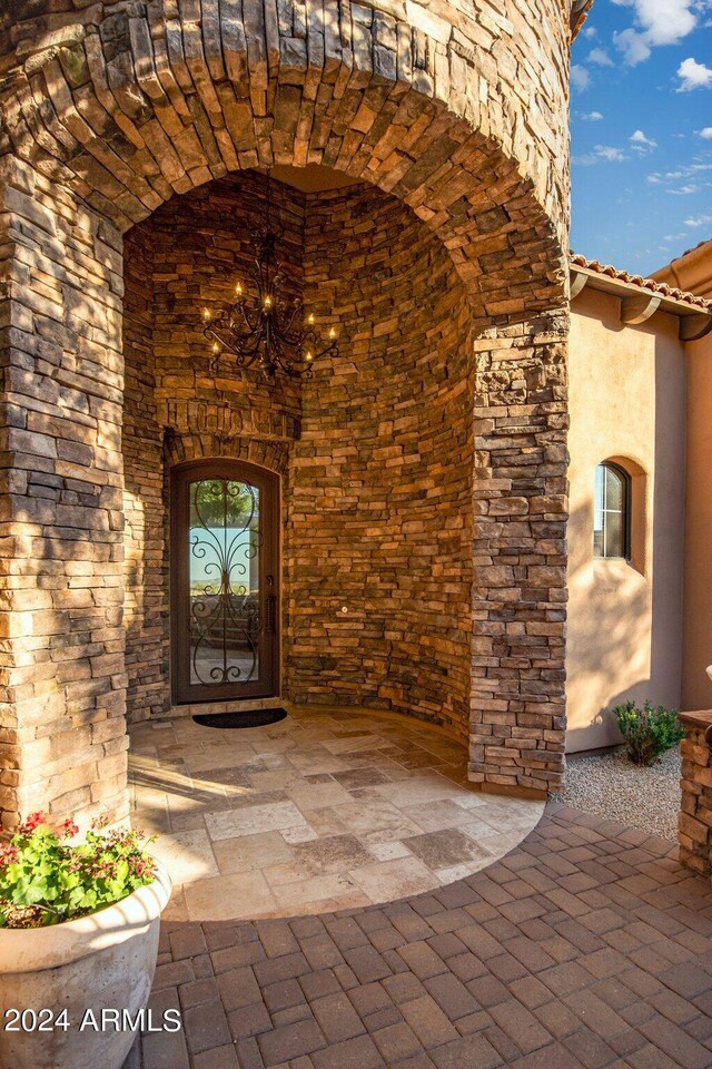 property entrance with stone siding, stucco siding, and a tile roof