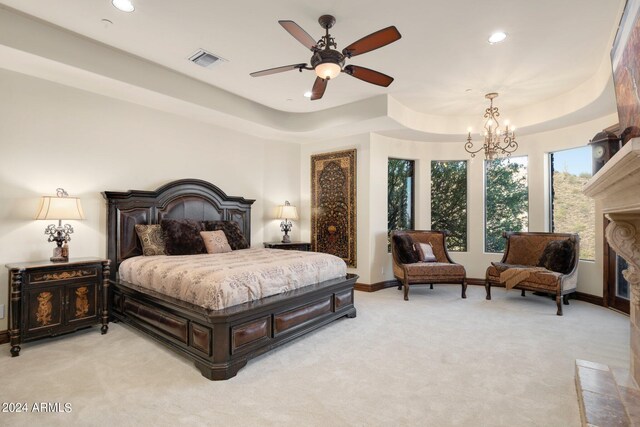 bedroom featuring ceiling fan with notable chandelier, light carpet, and a tray ceiling