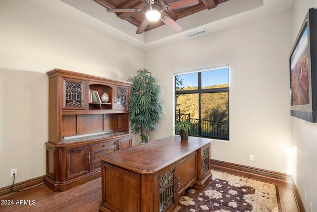 office featuring ceiling fan, a raised ceiling, dark wood-type flooring, and coffered ceiling