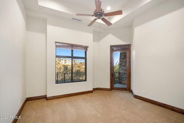 unfurnished room with light colored carpet, ceiling fan, and a tray ceiling