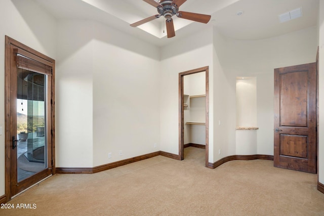 unfurnished bedroom with a spacious closet, a towering ceiling, ceiling fan, light carpet, and a closet