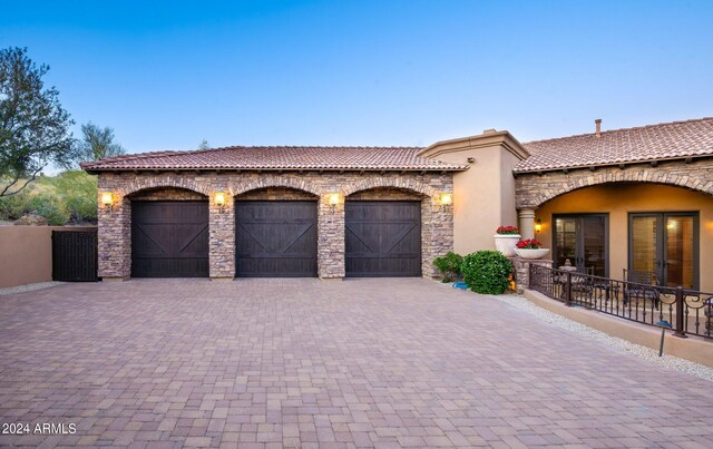 view of front of property with a tiled roof, stucco siding, decorative driveway, a garage, and stone siding