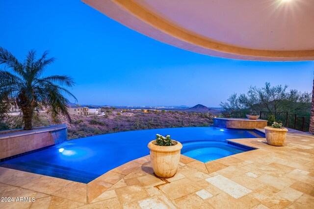 pool at dusk with an in ground hot tub