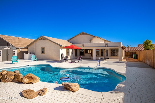 view of pool with a storage unit and a patio