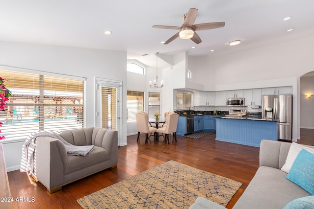 living room with sink, ceiling fan with notable chandelier, dark hardwood / wood-style floors, and high vaulted ceiling