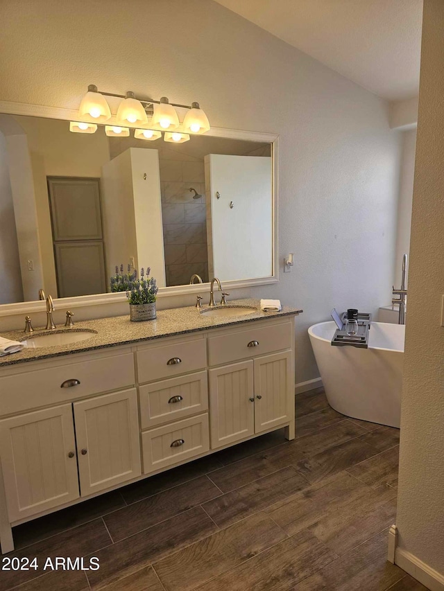 bathroom with hardwood / wood-style flooring, vanity, lofted ceiling, and plus walk in shower