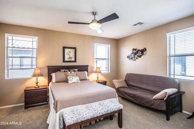 carpeted bedroom featuring multiple windows and ceiling fan