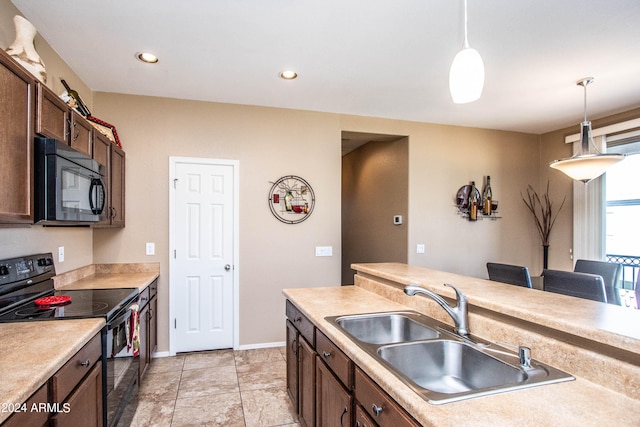 kitchen with a breakfast bar, hanging light fixtures, black appliances, and sink