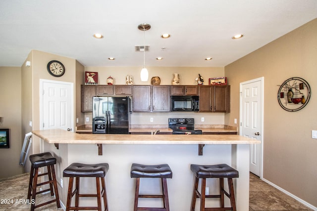 kitchen featuring black appliances, an island with sink, a kitchen bar, and dark brown cabinets