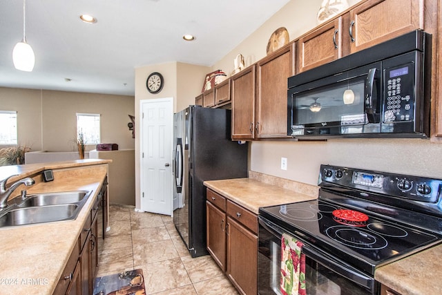 kitchen featuring sink, black appliances, hanging light fixtures, and light tile patterned floors