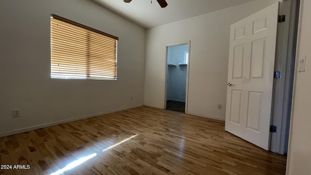 unfurnished bedroom featuring a walk in closet, ceiling fan, hardwood / wood-style floors, and a closet