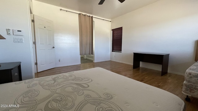 bedroom featuring hardwood / wood-style flooring, ceiling fan, and a barn door