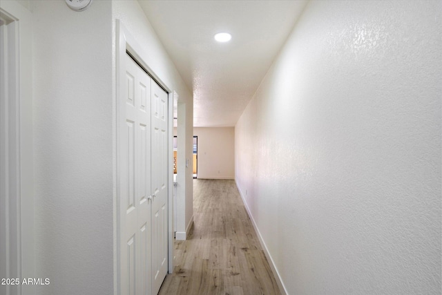 hall featuring light wood-type flooring, baseboards, and recessed lighting