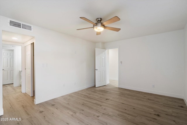 empty room with ceiling fan, light wood-style floors, and baseboards