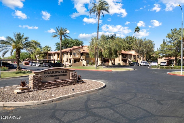community sign featuring uncovered parking and a residential view