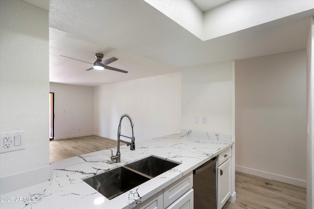 kitchen with dishwasher, a sink, light stone countertops, white cabinetry, and light wood-type flooring