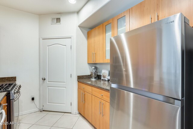 kitchen featuring dark stone counters, light tile patterned floors, and appliances with stainless steel finishes