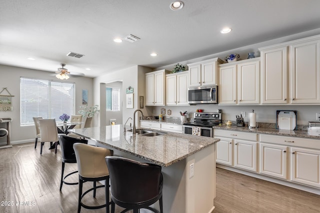 kitchen with light wood-style flooring, visible vents, stainless steel appliances, and a sink