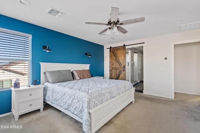 carpeted bedroom with a barn door and ceiling fan