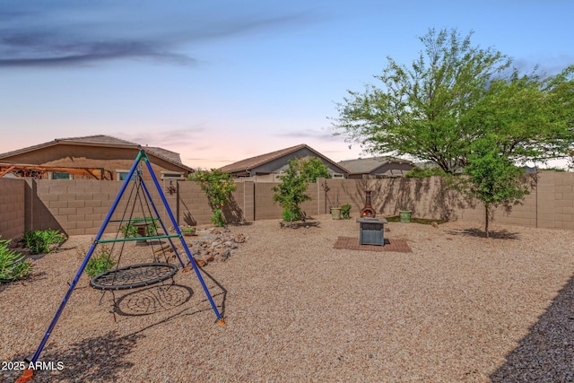 yard at dusk featuring a playground and a fenced backyard
