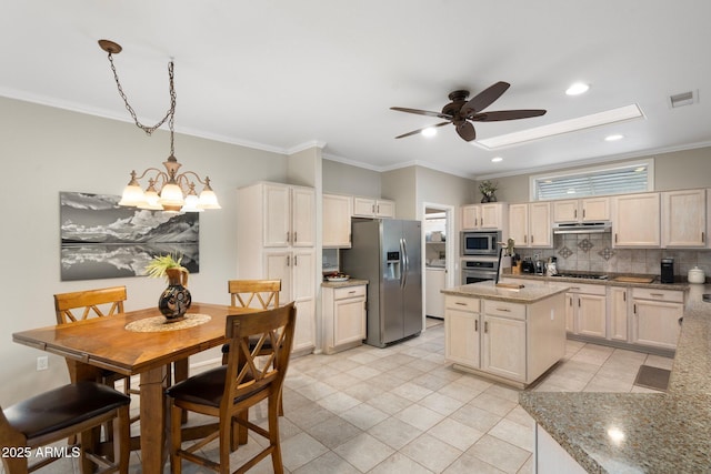 kitchen featuring under cabinet range hood, stainless steel appliances, visible vents, backsplash, and a center island