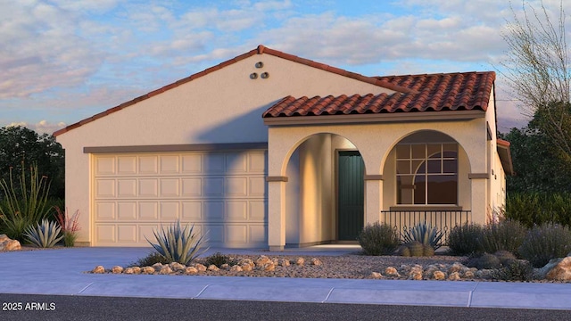 mediterranean / spanish home featuring a garage, stucco siding, driveway, and a tile roof
